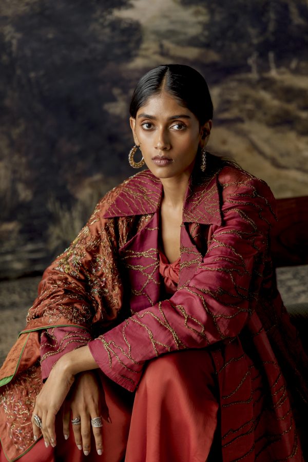 Model wearing the multi-hued jumpsuit with a jacket and stole, showcasing the antique embroidery and elegant design