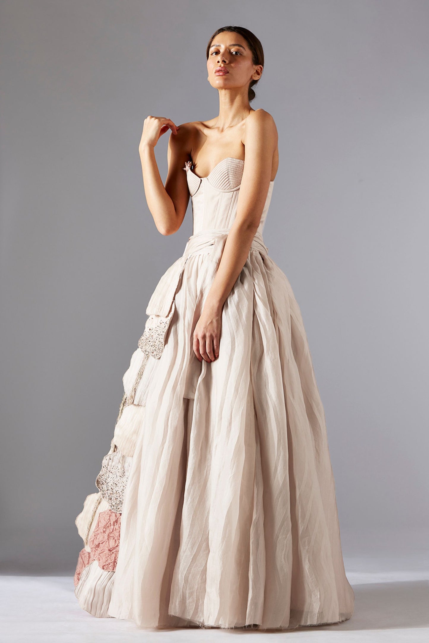 Full-body shot of a woman wearing the quilted corset, pleated skirt, and luxury laurel designer belt, creating an elegant ensemble