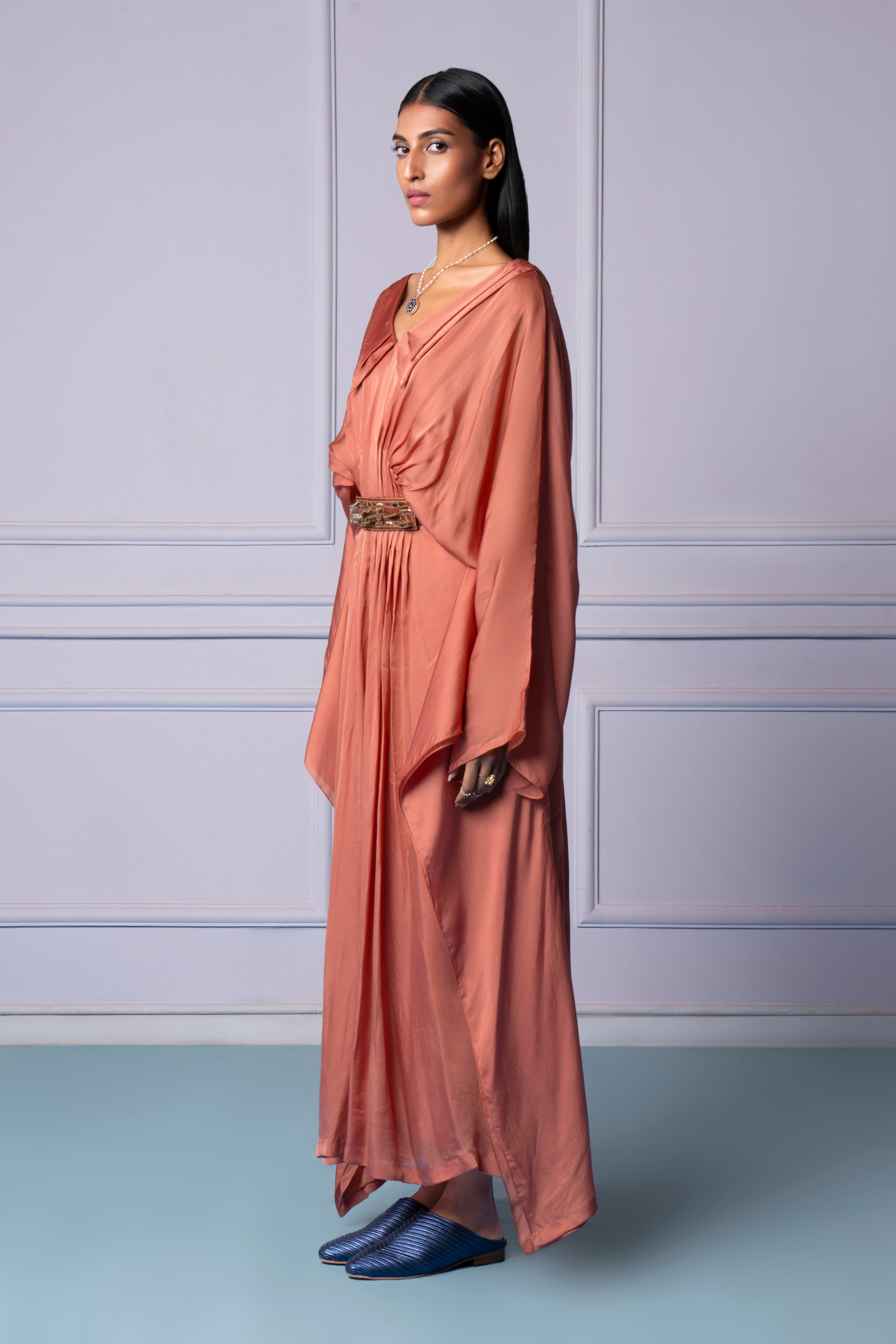 Side view of the rosewood pleated kaftan dress, emphasizing the graceful flow and tailored design with double collar