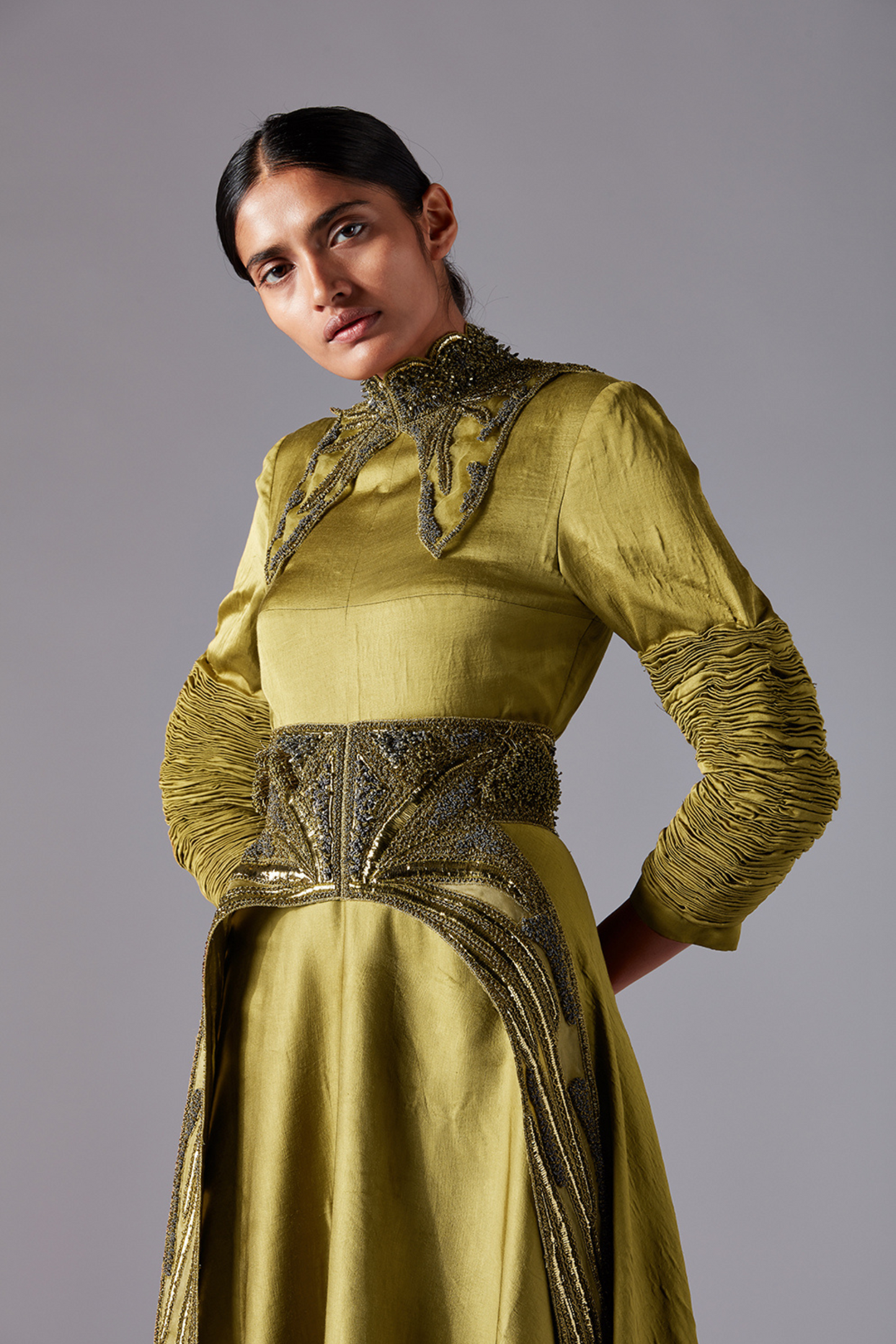 Close-up view of the sculpted sleeves and metallic accents on the designer gown
