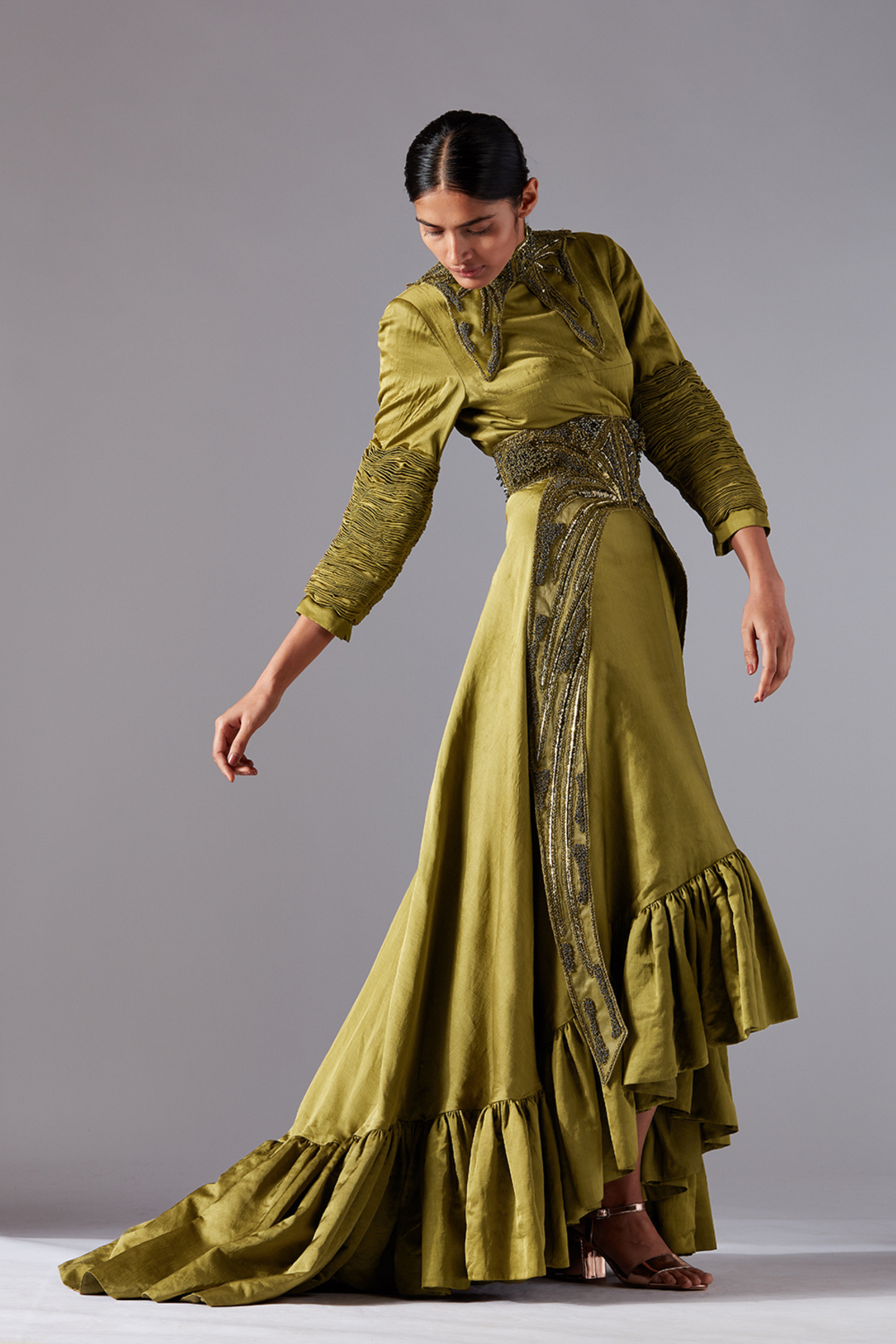 Woman confidently wearing the stylish designer gown with sculpted sleeves and flounced trail, perfect for formal occasions