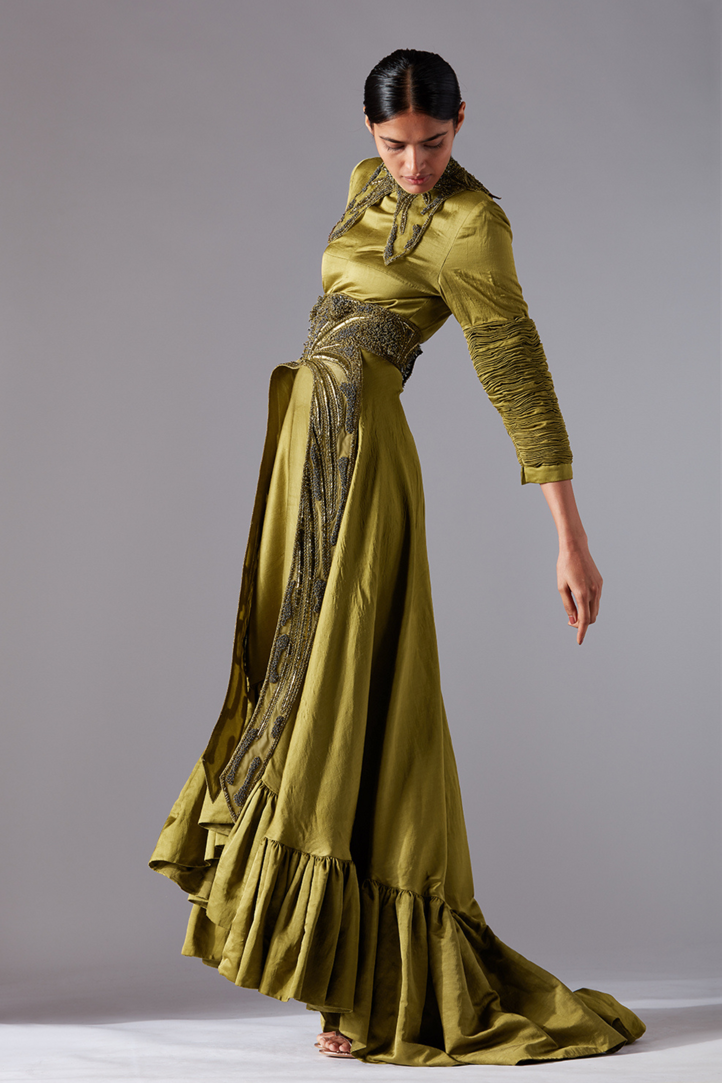 Side profile of a woman in the designer gown, showcasing the elegant silhouette and flowing trail