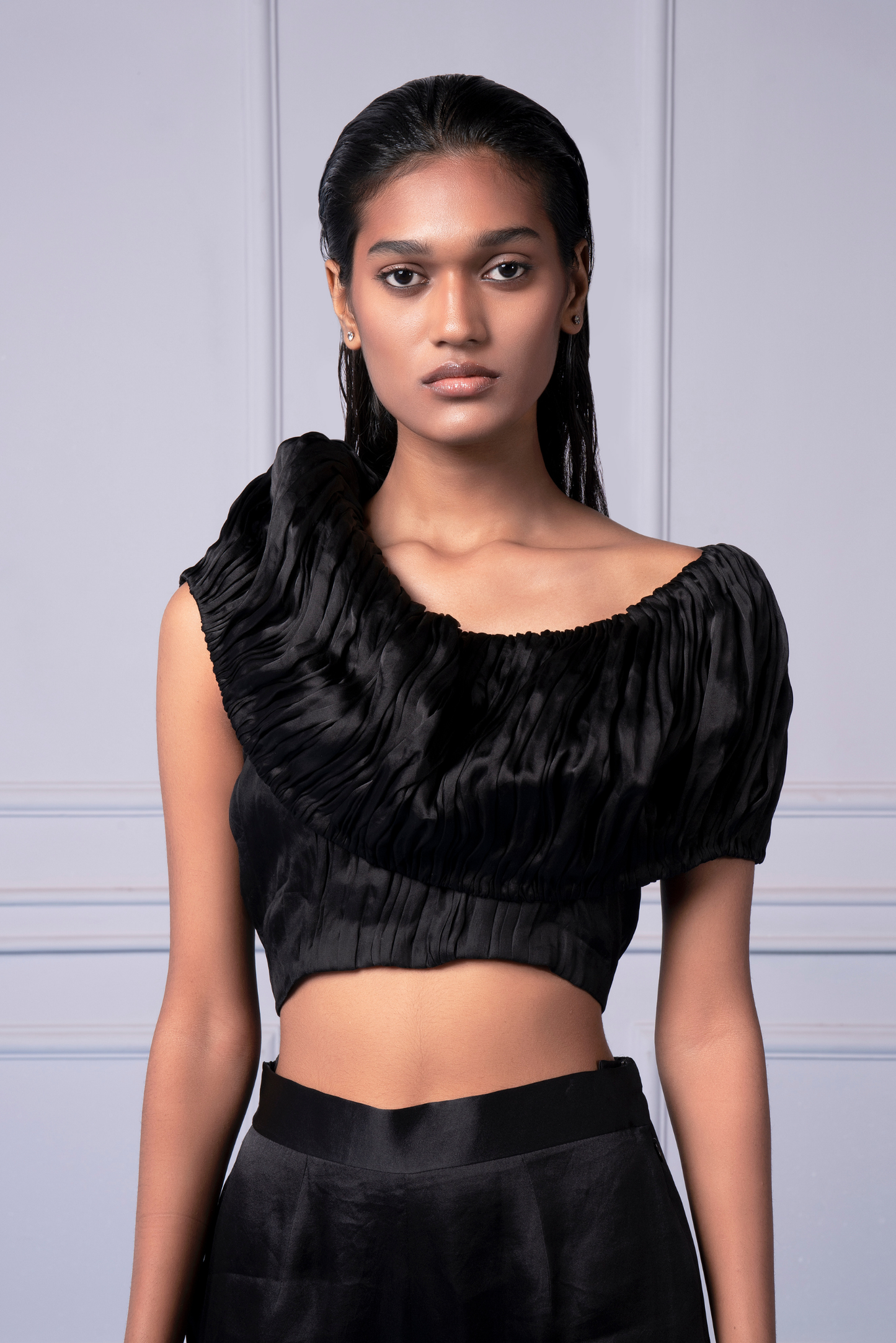 Close-up view of the hand-ruched satin design on the black crop top