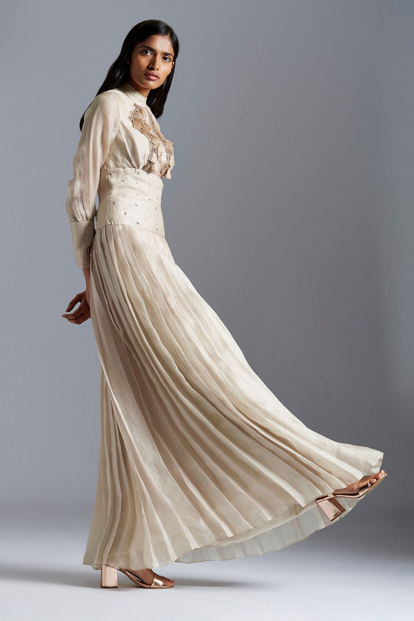 Side profile of a woman in the Victorian designer gown, highlighting the pleated details and elegant silhouette