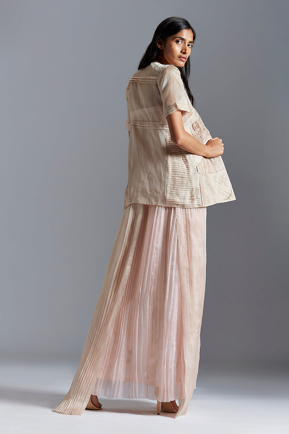 Back view showing the pleated design of the tube dress and the intricate fabric details on the designer sheer jacket
