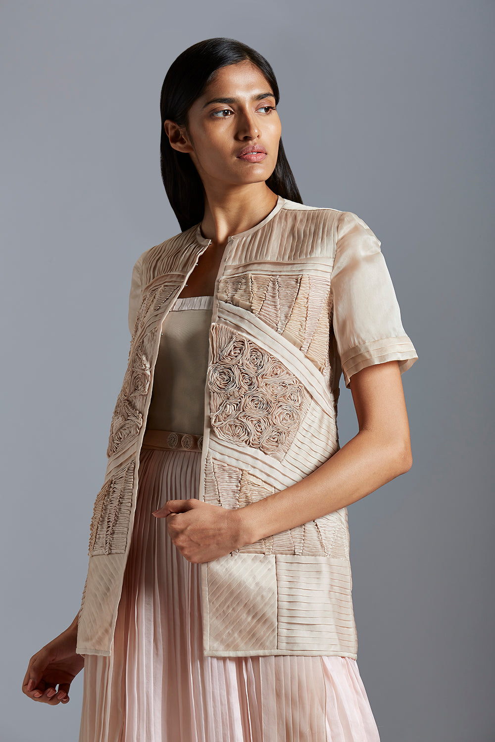 Close-up view of the fabric details on the sheer designer jacket and the pleated texture of the tube dress