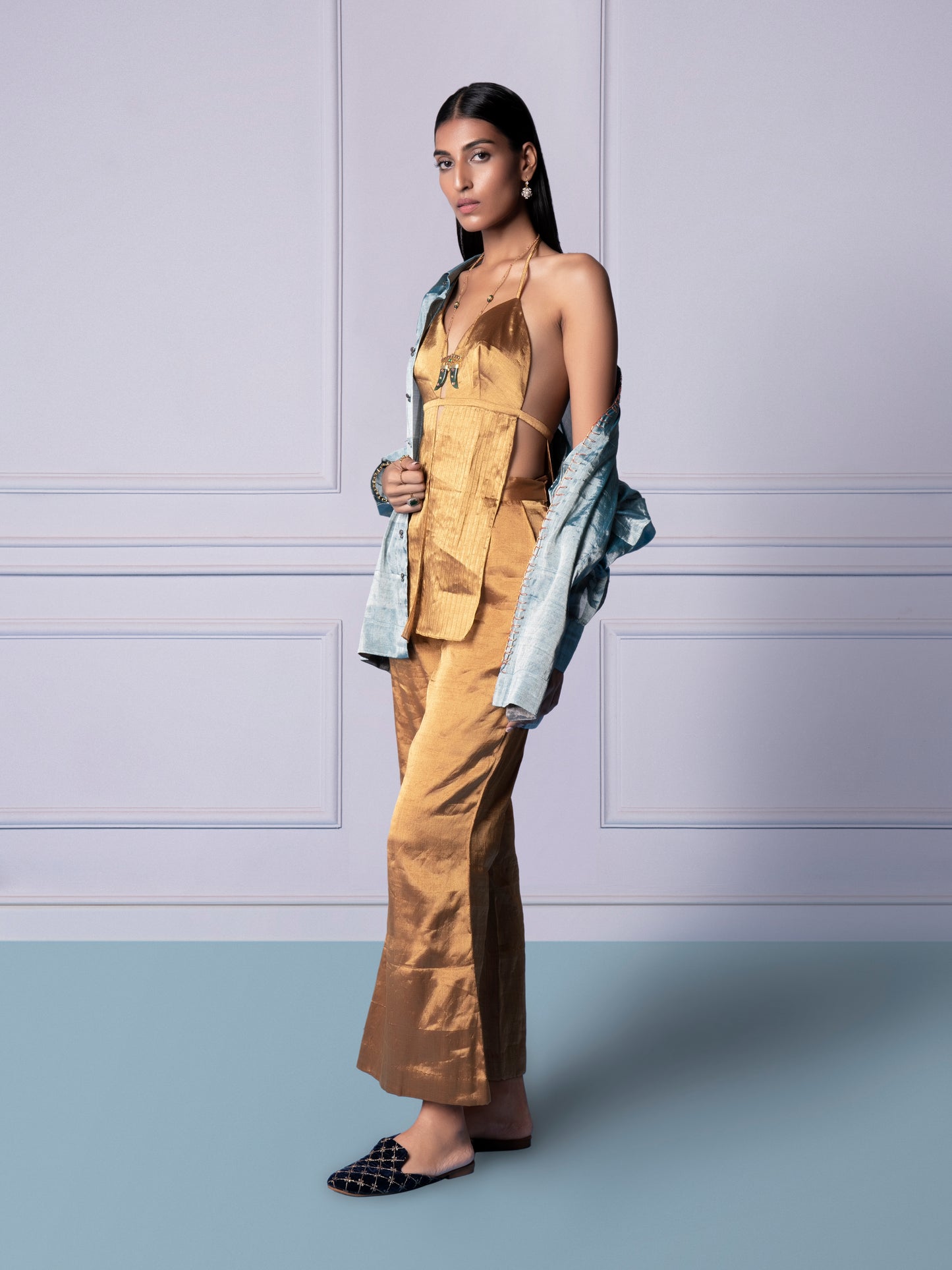 Model wearing Gold Chanderi bralette, gold trousers, and blue shirt, embodying a chic and fashionable luxury look