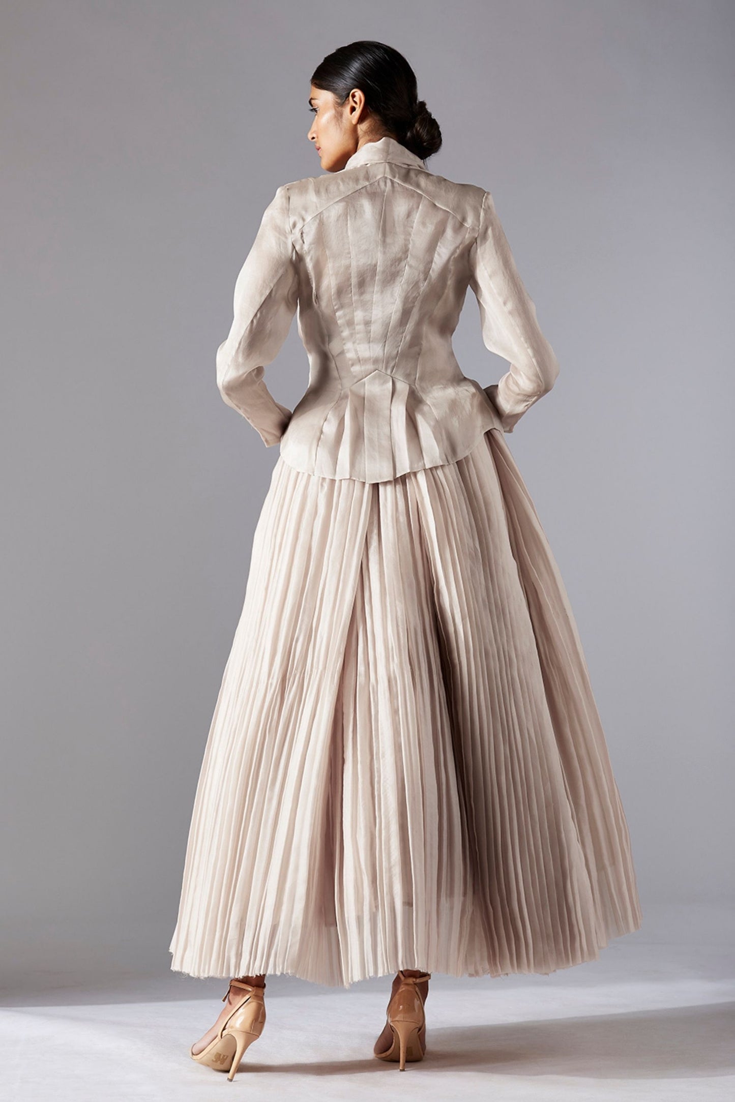 Back view highlighting the flow of the pleated ballroom skirt and the sophisticated design of the sheer organza jacket