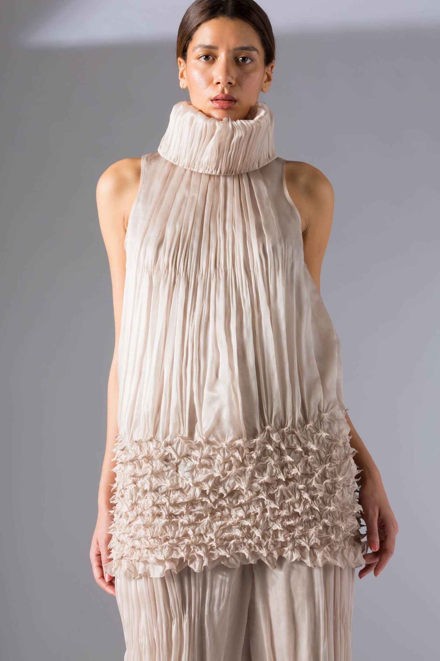 Close-up of the rouched drop-waist top and sculpted narrow pants, showcasing the intricate details and modern design