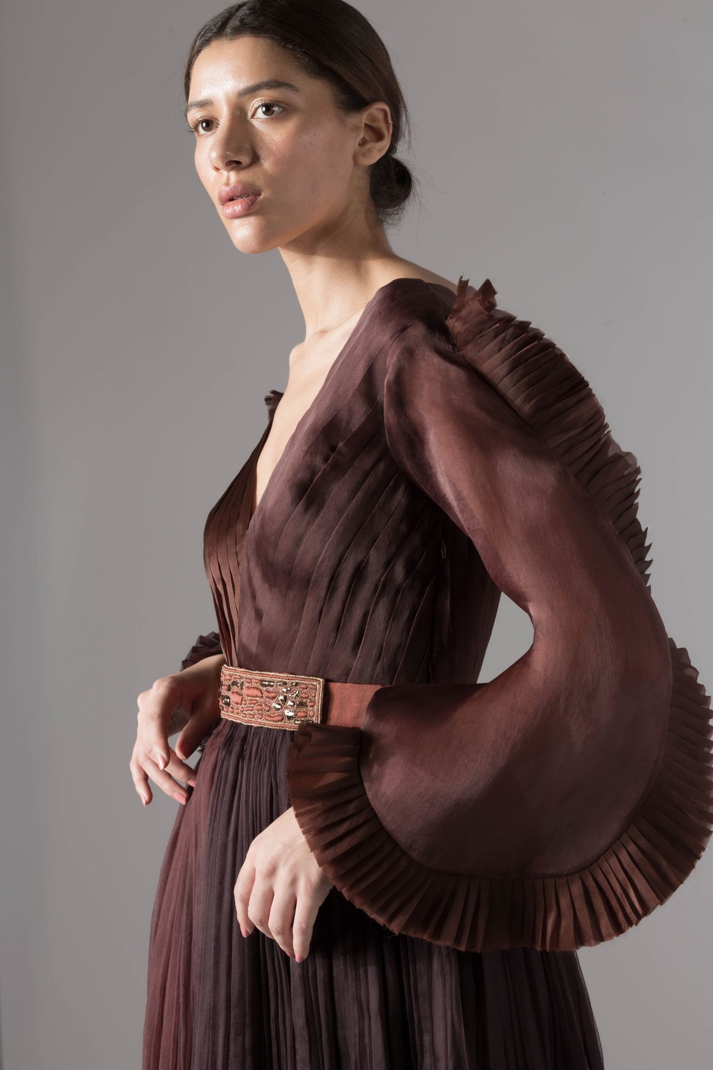 Side view of the stylish evening gown, emphasizing the elegant silhouette, pleated ruching, and bold statement sleeves
