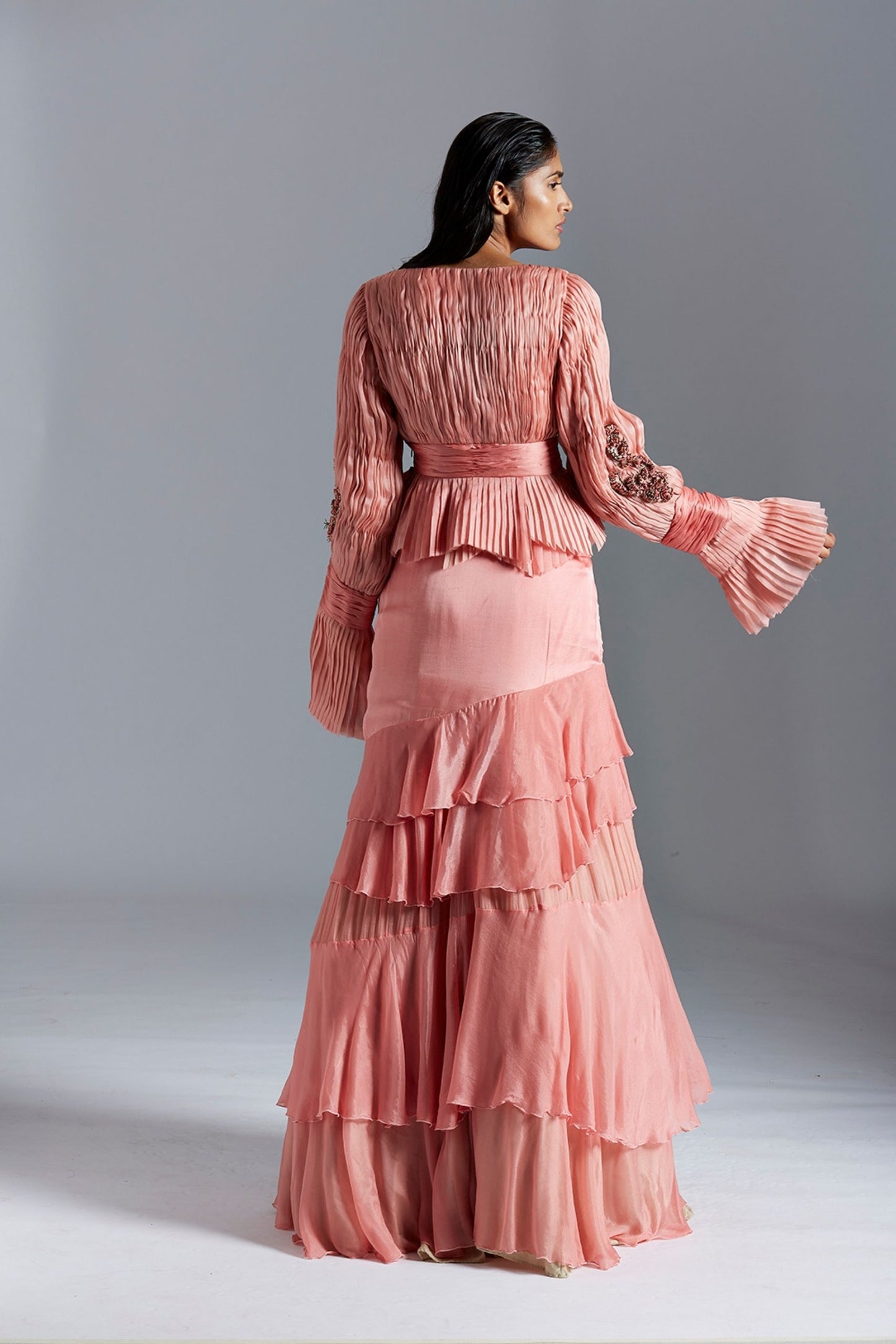 Back view of the peplum top and flared satin skirt, highlighting the modern design and elegant fit