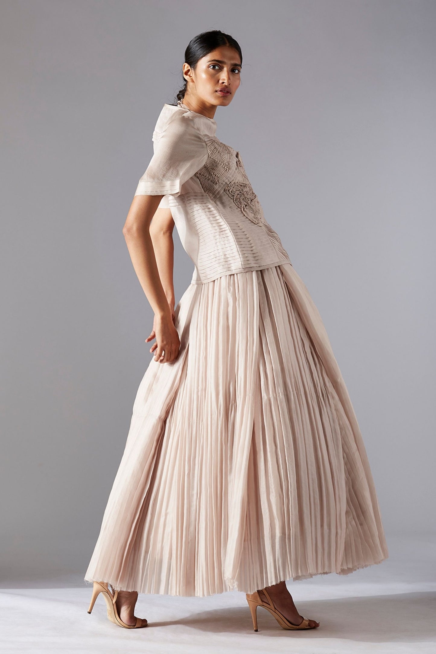 Side profile of a woman showcasing the elegant silhouette of the designer jacket and pleated ballroom skirt