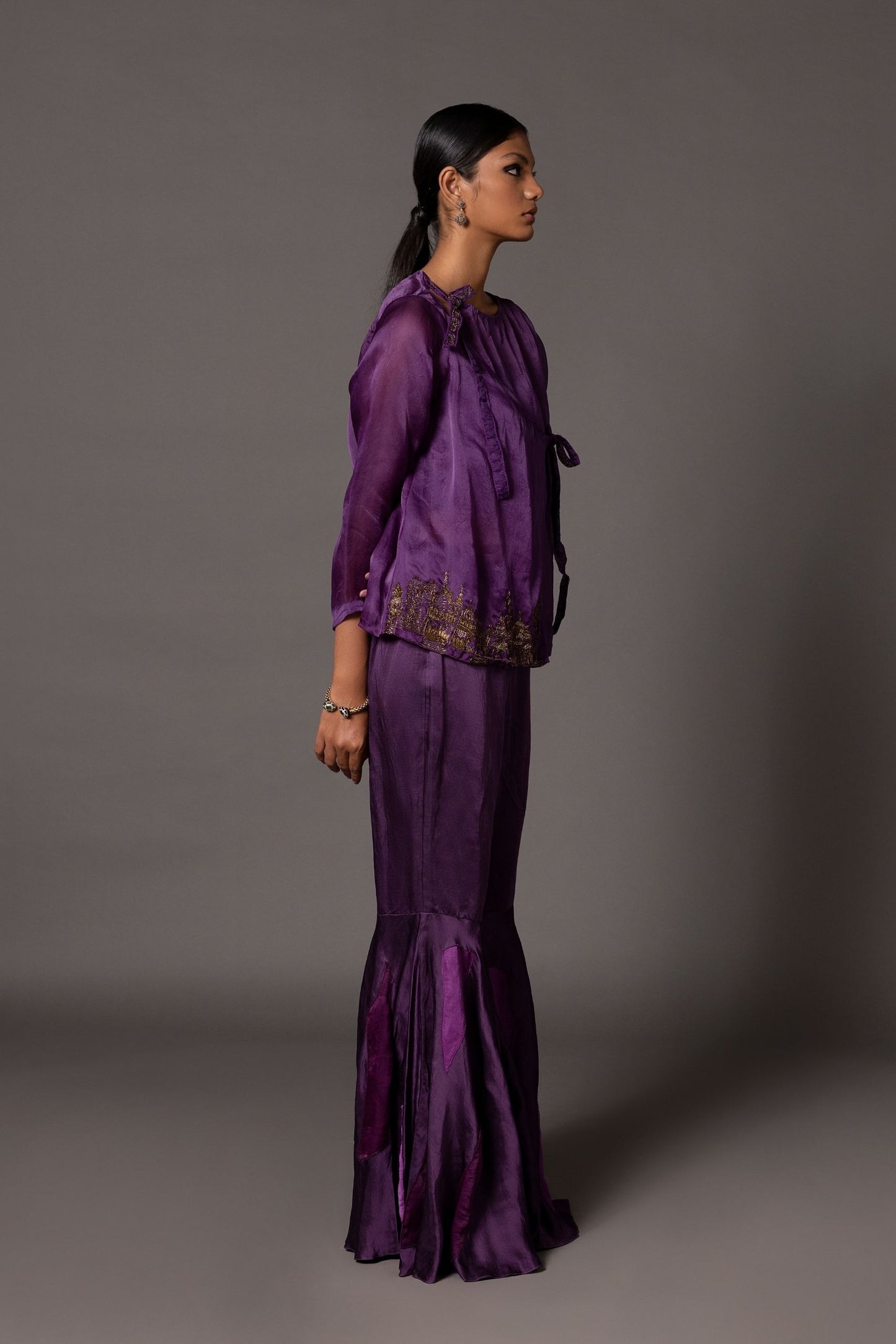 Side view of the purple Angrakha top with metallic embroidery and the fit-and-flare silhouette of the color-blocked gharara pants