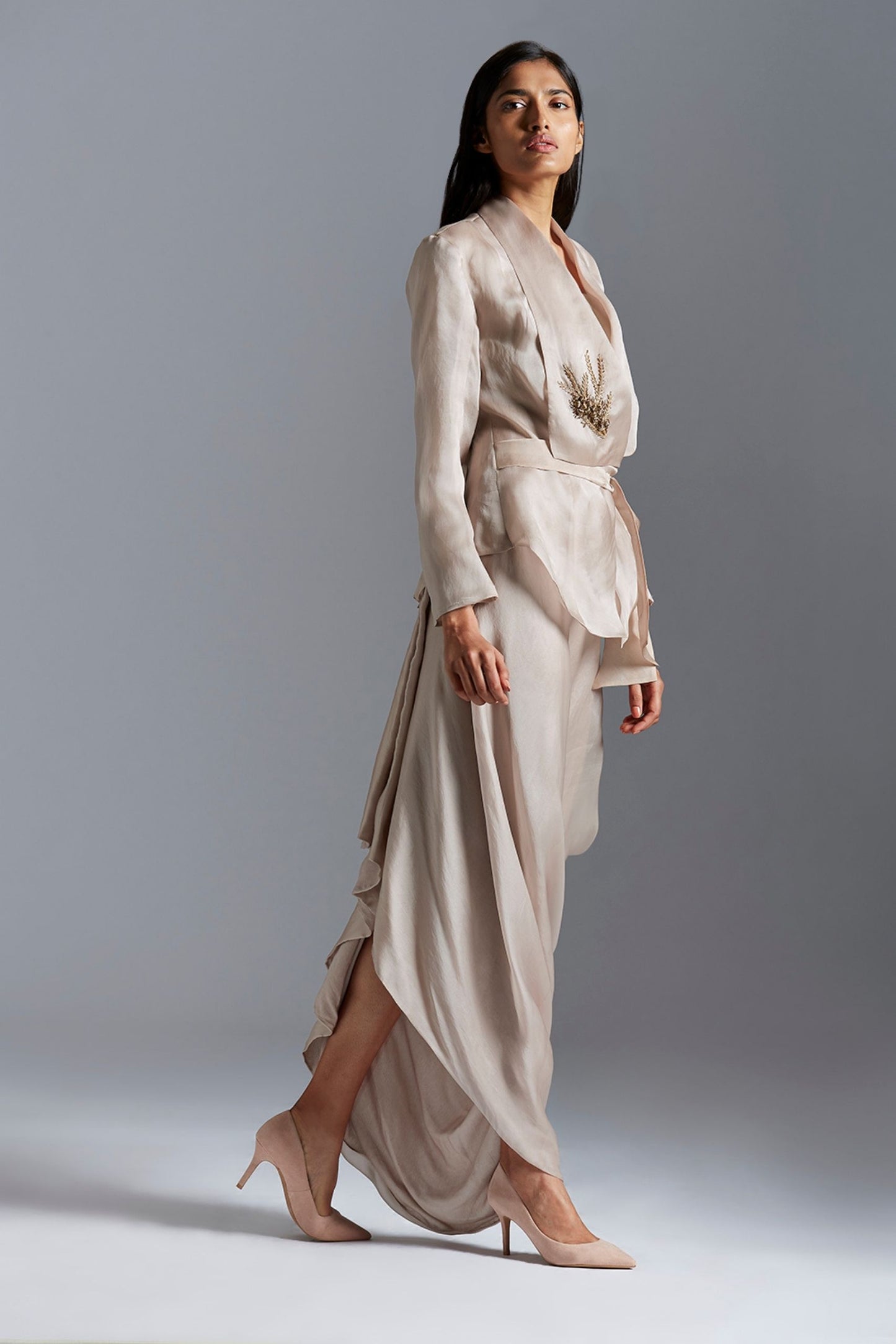 Side profile of a woman in the stylish designer jacket and drape skirt, highlighting the graceful flow and structured fit
