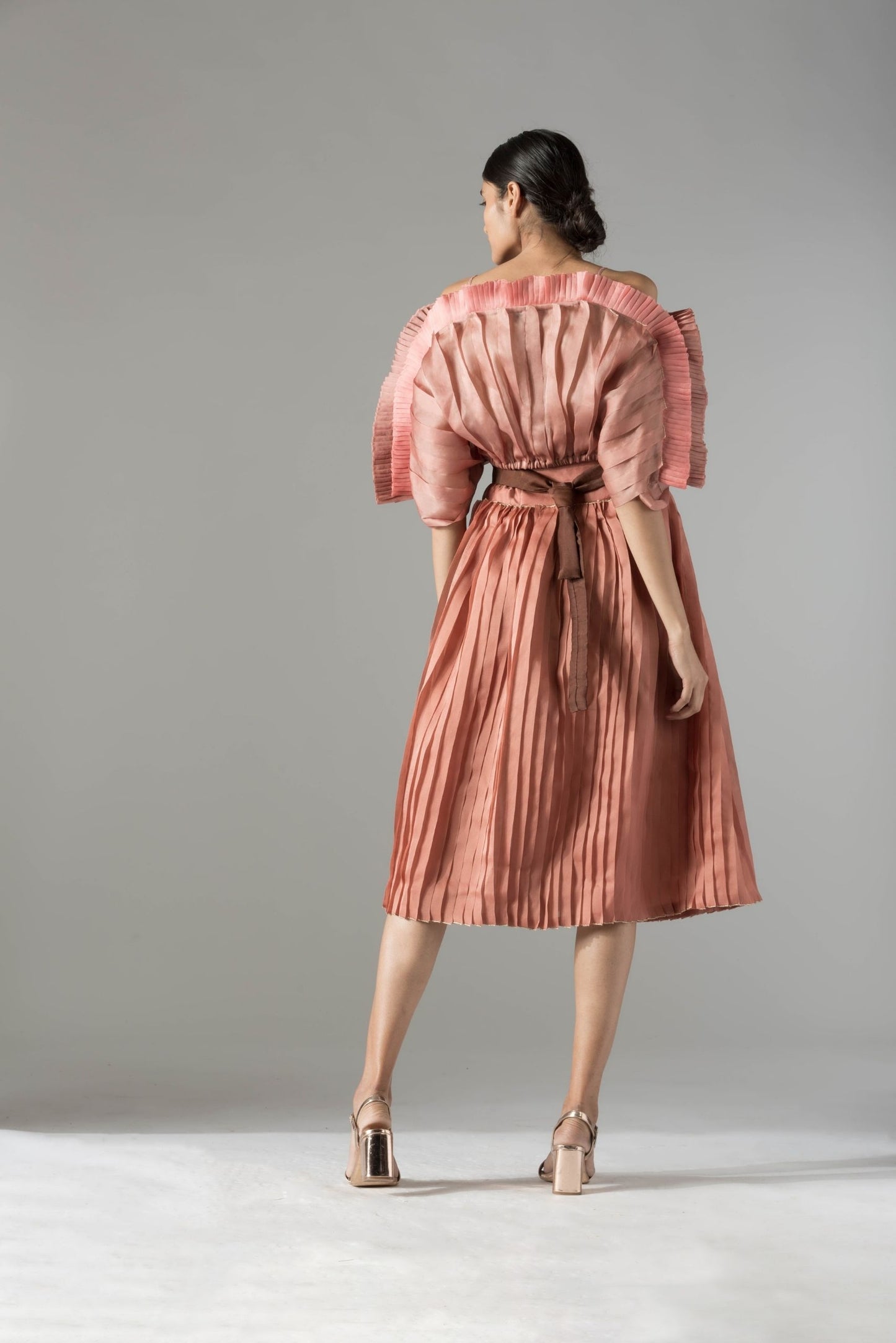 Back view of the stylish off-shoulder mushroom top and pleated skirt set, emphasizing the sleek silhouette and rope-inlay belt