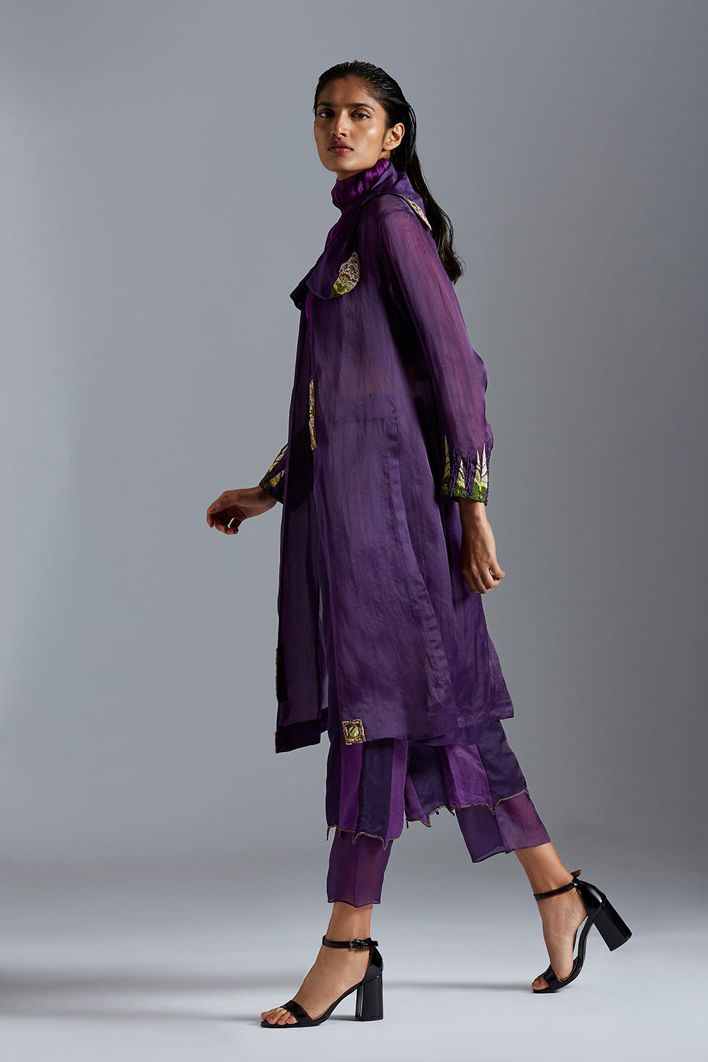 Side view of the top pant set, emphasizing the sleek design of the carpet long jacket, ruched crop top, and color-blocked pants