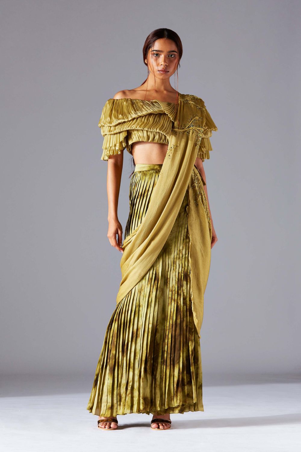 Off-shoulder blouse paired with a pleated skirt and embroidered stole, styled for a modern, elegant look