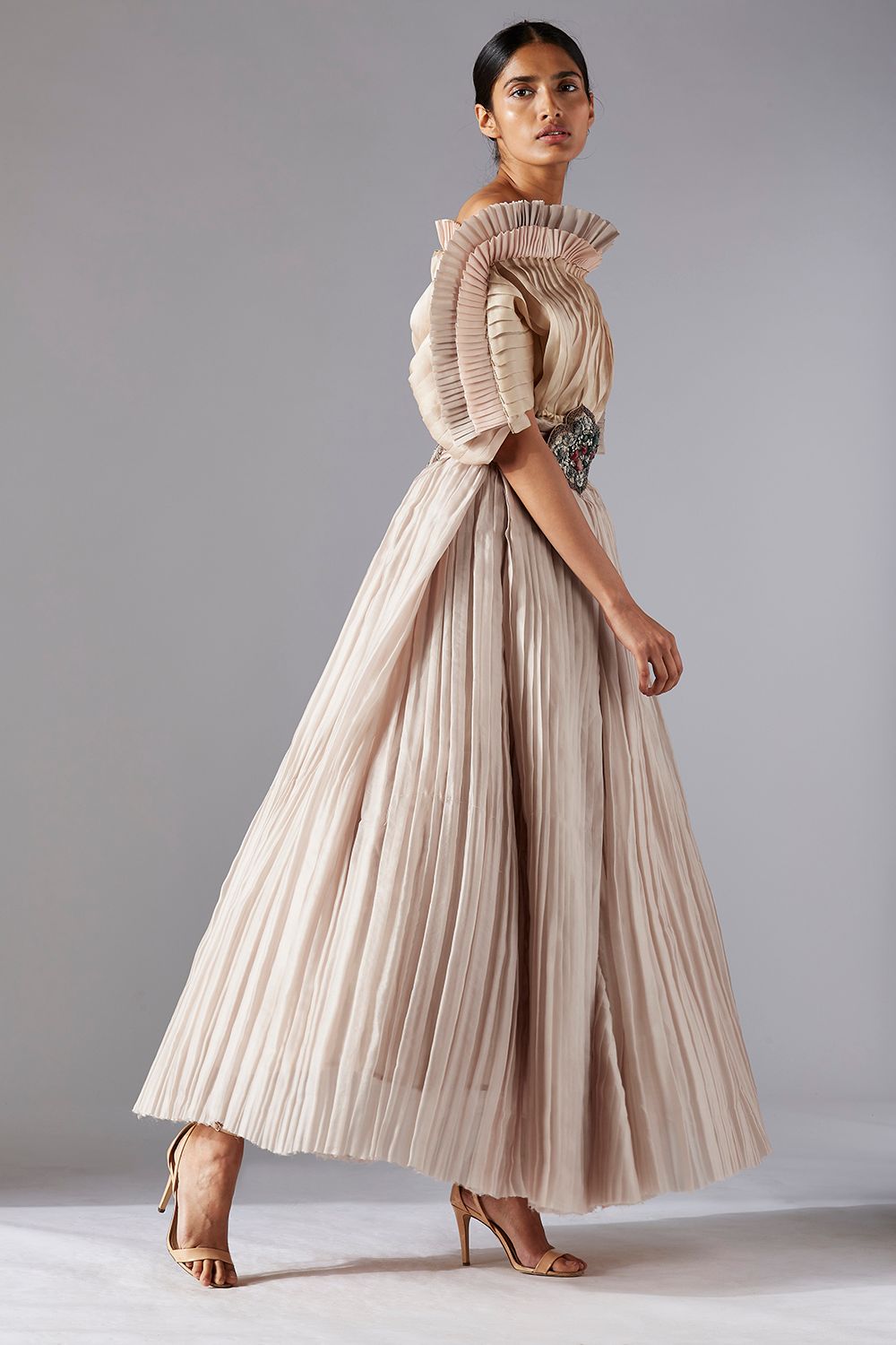 Side profile of a woman in the avant-garde pleated top and ballroom skirt, highlighting the modern, dramatic silhouette